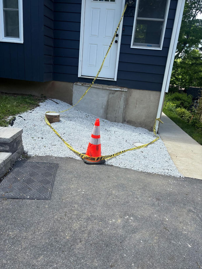 Orange cone on gravel path near building entrance.