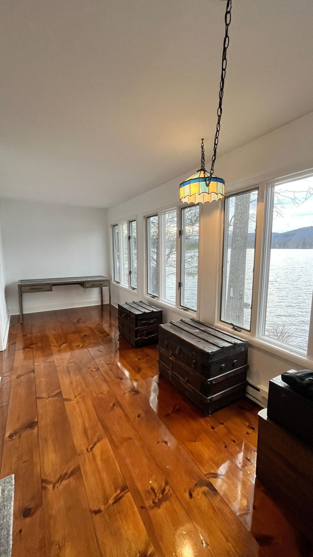 Room with wooden floor, large windows, and a desk.