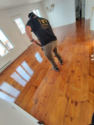 Person polishing a wooden floor in a bright room.