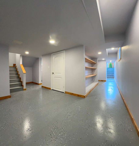 Basement with gray flooring and recessed lighting.
