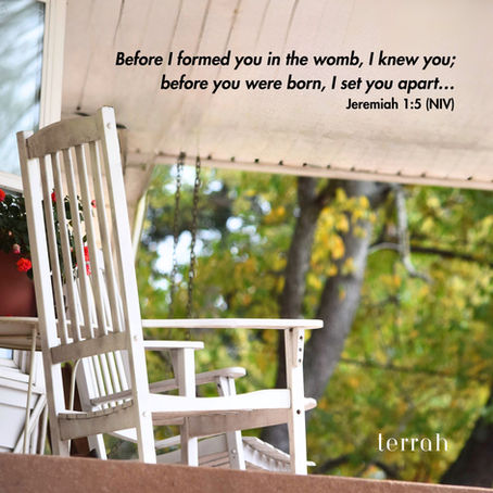 White rocking chair on porch with potted pink flowers and trees in the background, with scripture verse Jeremiah 1:5.