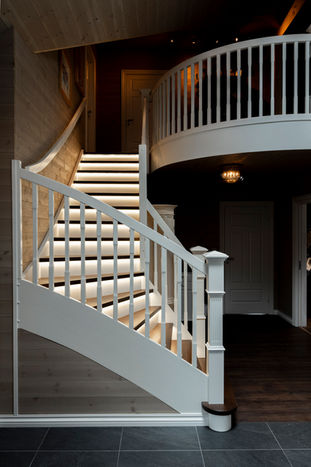 Klassisk og herskapelig trapp med Empire stoler og spiler. Led-striper under trinnene. Buet rekkverk i andre etasje og blokktrinn i starten av trappa