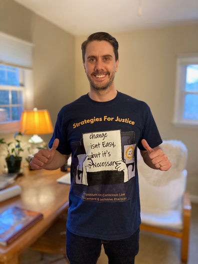 A white man with brown hair named Brad, wearing a Strategies for Justice 2021 Symposium Shirt.