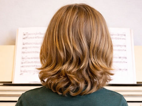 Boy playing the piano at home, focused on the keys and exploring music