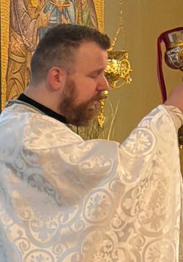 Priest in white vestments holding golden chalice