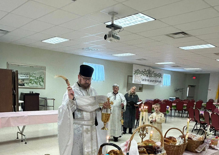 Priest blessing traditional Easter food baskets on a table