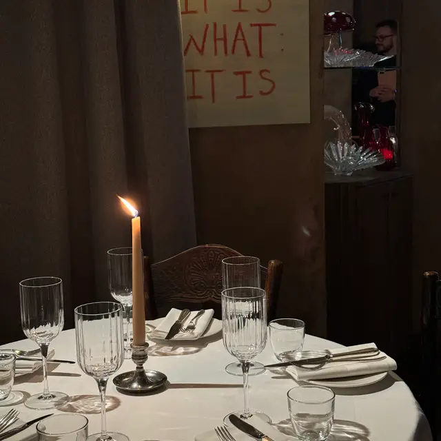 A dark intimate restaurant with candle lit tables and an open kitchen 