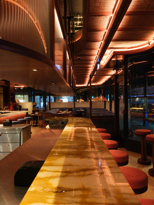 A dimly lit restaurant with open kitchen and bar seating