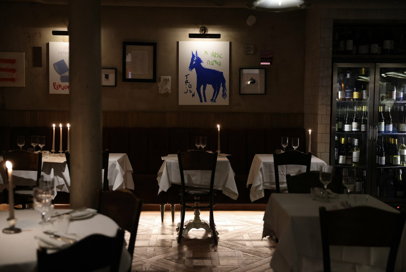 A dark intimate restaurant with candle lit tables and an open kitchen