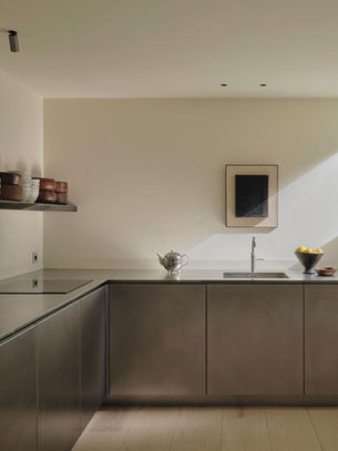 Stainless steel kitchen with ceramic pottery and artworks in a light-filled room