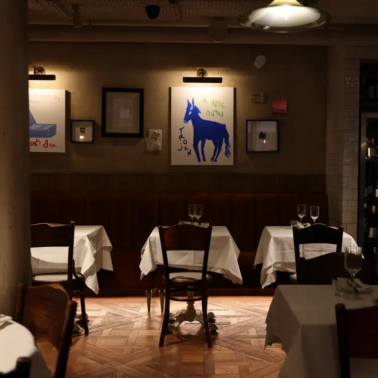 A dark intimate restaurant with candle lit tables and an open kitchen 