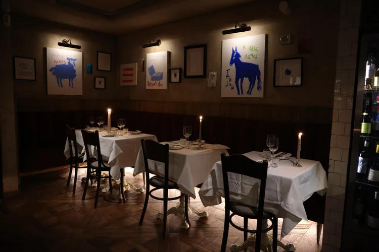 A dark intimate restaurant with candle lit tables and an open kitchen 