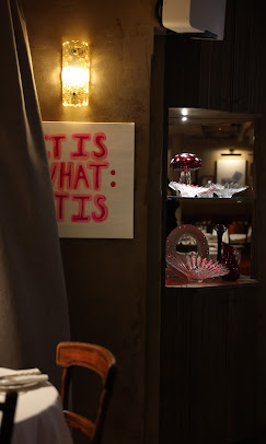 A dark intimate restaurant with candle lit tables and an open kitchen 