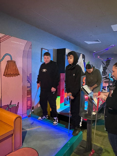 Two men in a colorful indoor mini-golf course