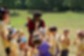 A counselor in a red, velvet coat passing out paper crowns to excited campers