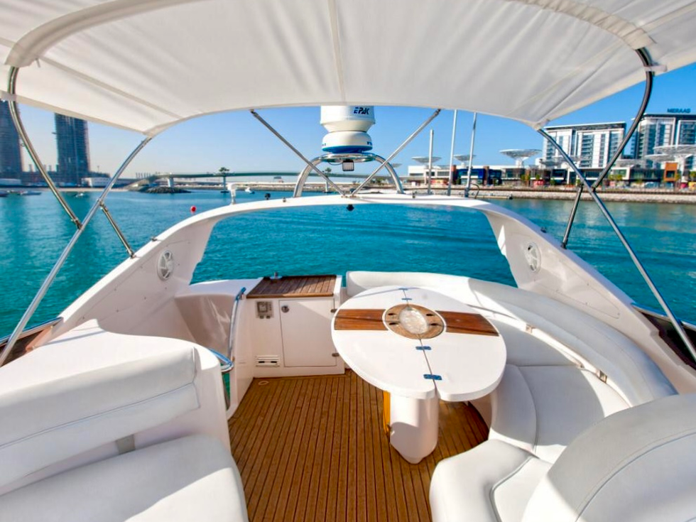 Luxury yacht interior with table and seating overlooking turquoise waters in Dubai.