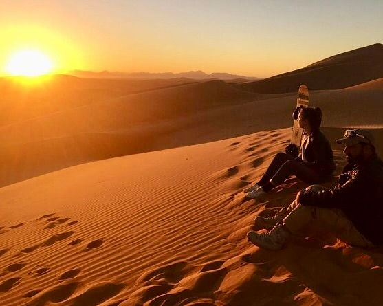 People watching the sunset on sand dunes; Red Dunes Desert Safari in Dubai