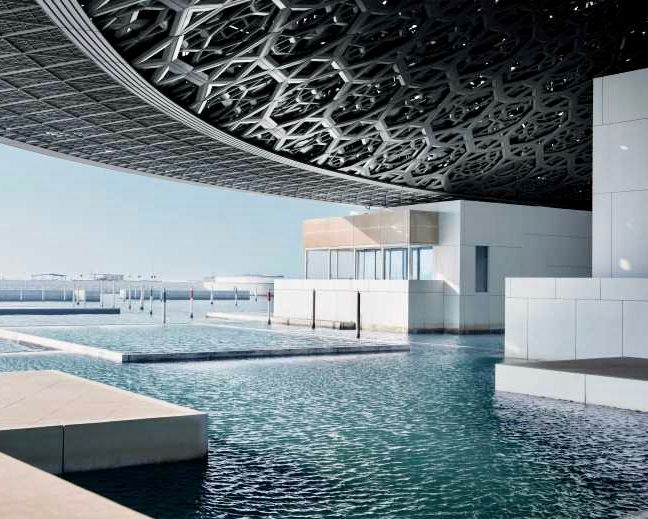 Exterior view of Abu Dhabi Louvre Museum, pool and architectural design.