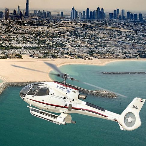 Helicopter flying over Dubai with buildings DUBAI DOO visible in background and water