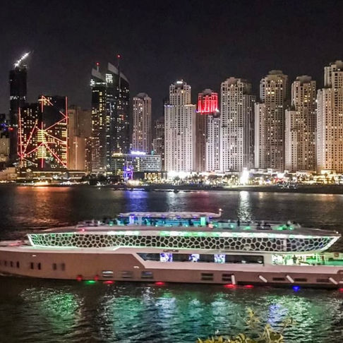 Night cruise on the water with city lights. Skyscrapers in the background.