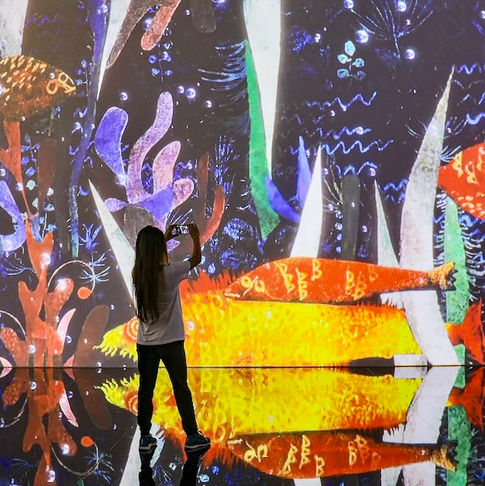 Woman in front of colorful art installation, reflecting on mirrored floor DUBAI DOO