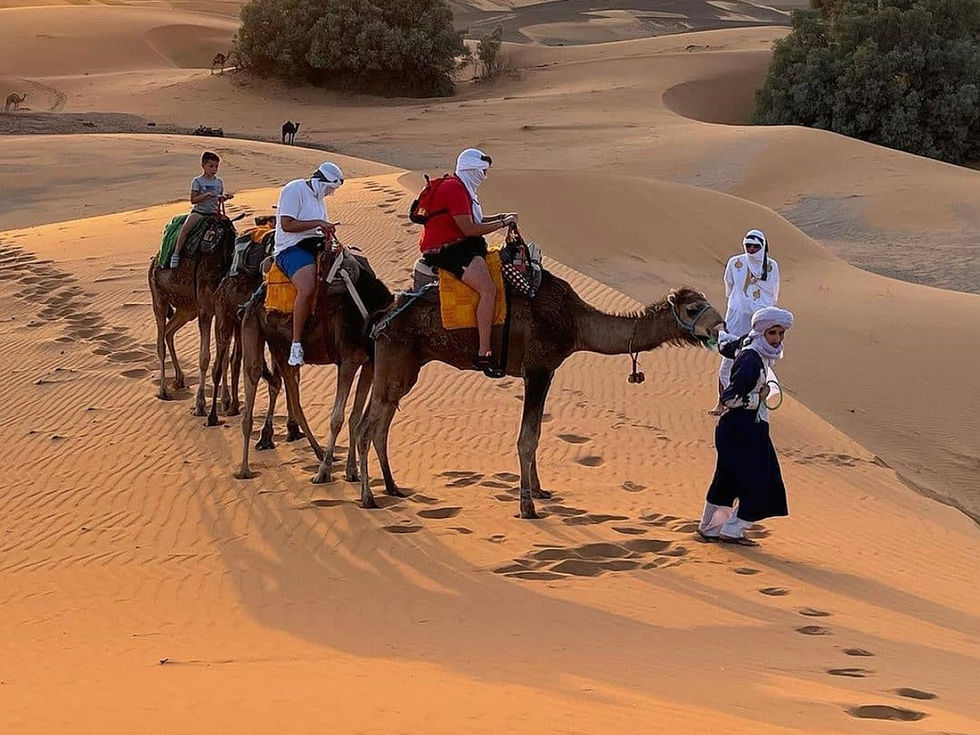 People riding camels in the desert, enjoying a beautiful, sunny day.