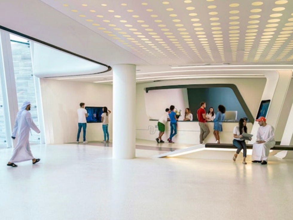 People in modern reception area; white decor and screen; DUBAI DOO.