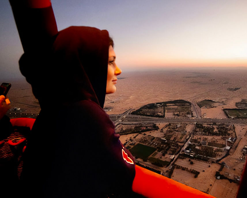 Woman in black hoodie looking at the city during sunset.