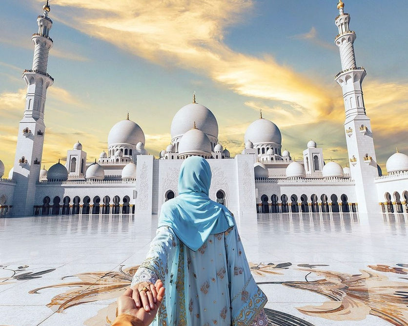 Woman in blue hijab holds hand at Sheikh Zayed Grand Mosque, Abu Dhabi.