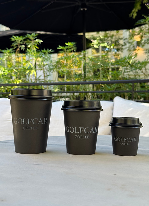 Trio of matte-black GOLFCAR Coffee cups on marble, showcasing refined takeaway presentation.