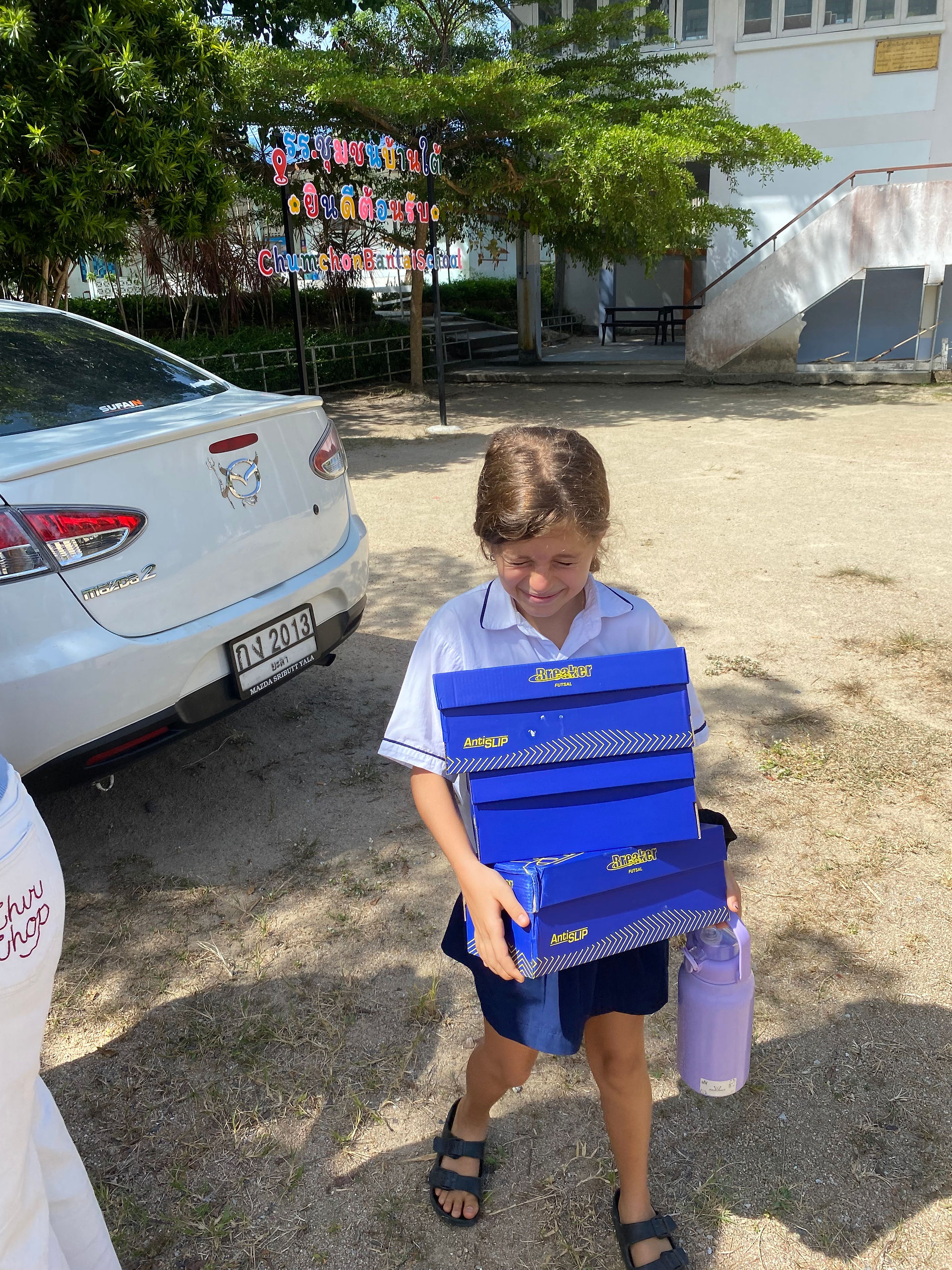 Student carrying shoeboxes for Si Ri Panya News Highlights.