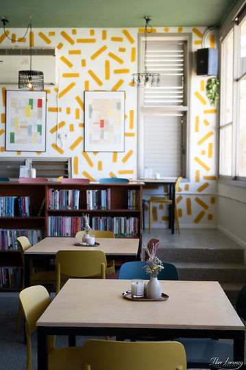 מועדון הספרייה מולדת, מבט אל הקיר עם הפסים הצהובים ושולחנות היישיבה בין הספרים