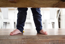 Close up picture of little kid feet standing on a kitchen table bench of a South Jordan, utah home