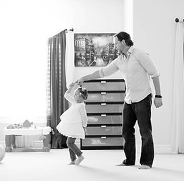 dad twirls his little girl by the hand in master bedroom of their Herriman City, utah home