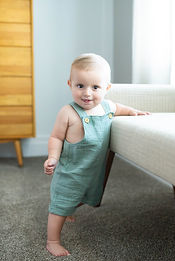 baby practices standing against a bench in his parent's master bedroom in Salt Lake City, utah