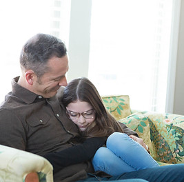 dad and little girl snuggle on living room sofa of their South Jordan city, Utah home