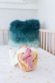 newborn baby curls up in the crib in nursery of their Salt Lake City, utah home