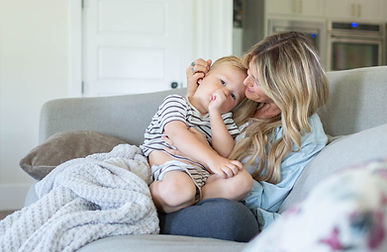 mom snuggles her preschooler on the living room couch of their South Jordan, Utah home