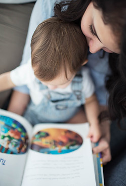 mom reads to toddler sitting in her lap in the rocking chair of their South Jordan, Utah nursery