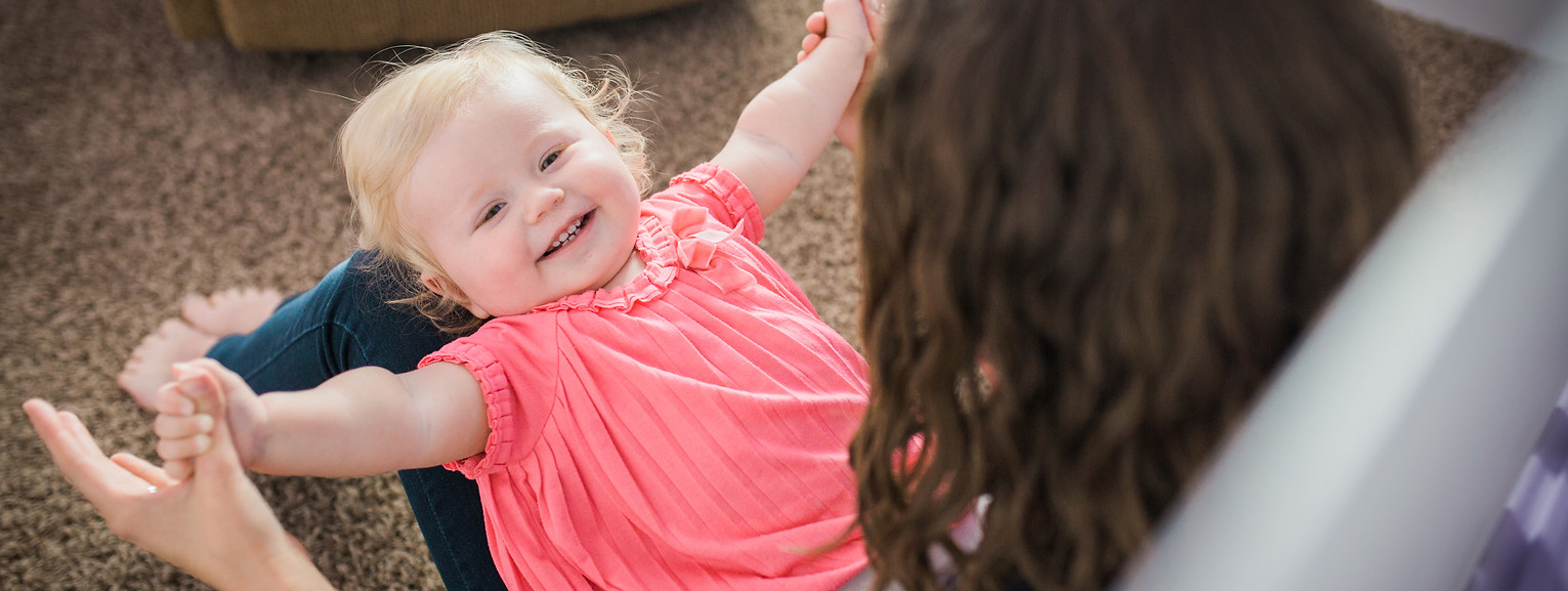 mom holds her baby in her lap and plays a game with her hands in the nursery of their Salt Lake City, utah home