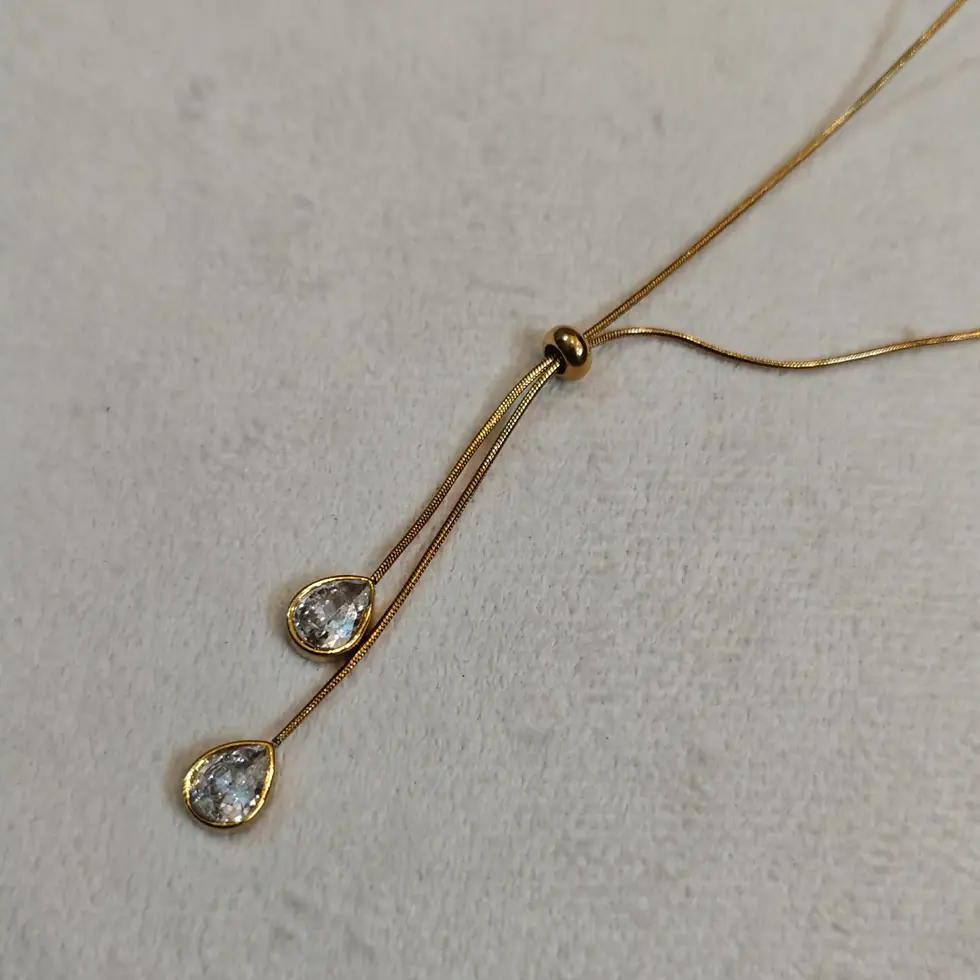 Elegant gold lariat necklace featuring two sparkling crystal teardrop pendants suspended from delicate fine chains.