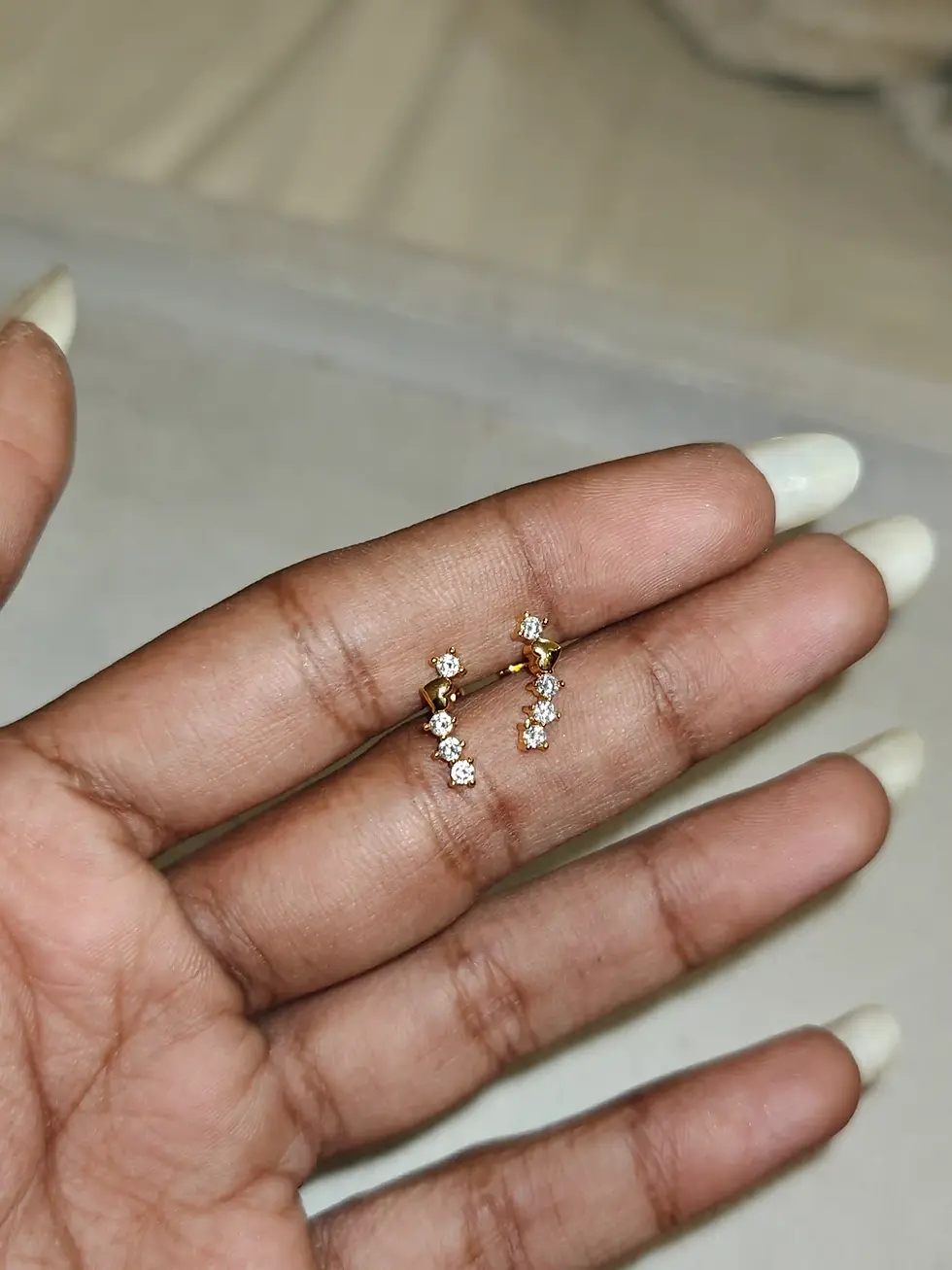 Delicate gold-plated climber stud earrings featuring a cascading arrangement of sparkling clear stones in a sleek, minimalist
