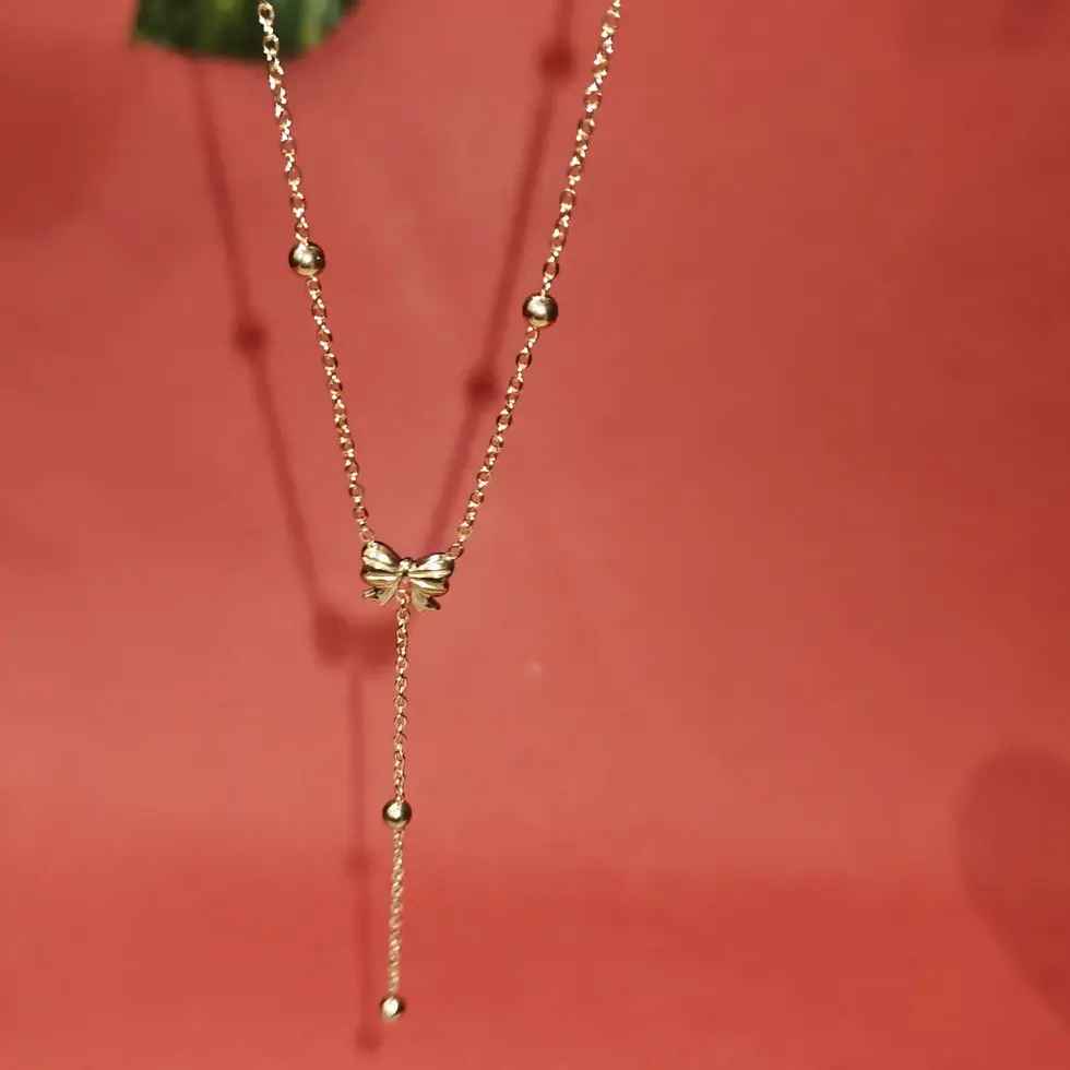 Elegant gold Y-necklace featuring delicate bead details and a sleek drop pendant design on a fine chain.