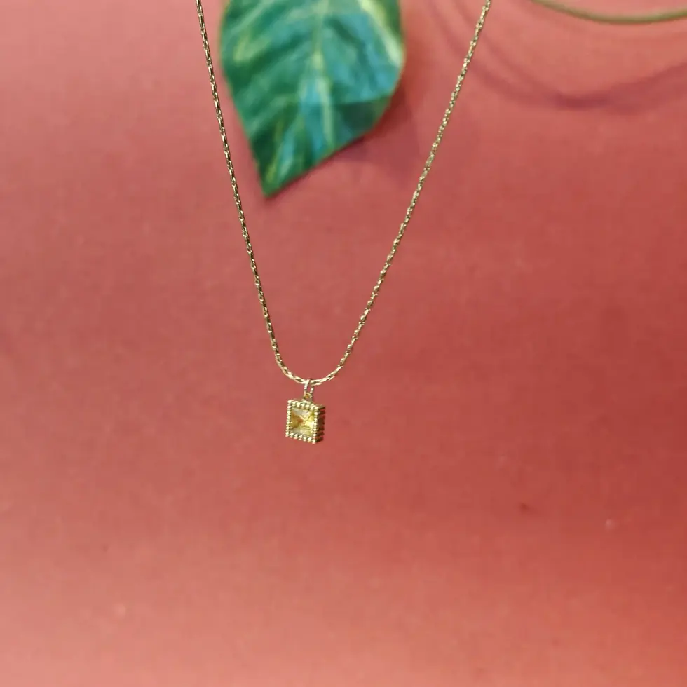 Gold-toned necklace with a small square crystal-studded pendant on a fine chain.