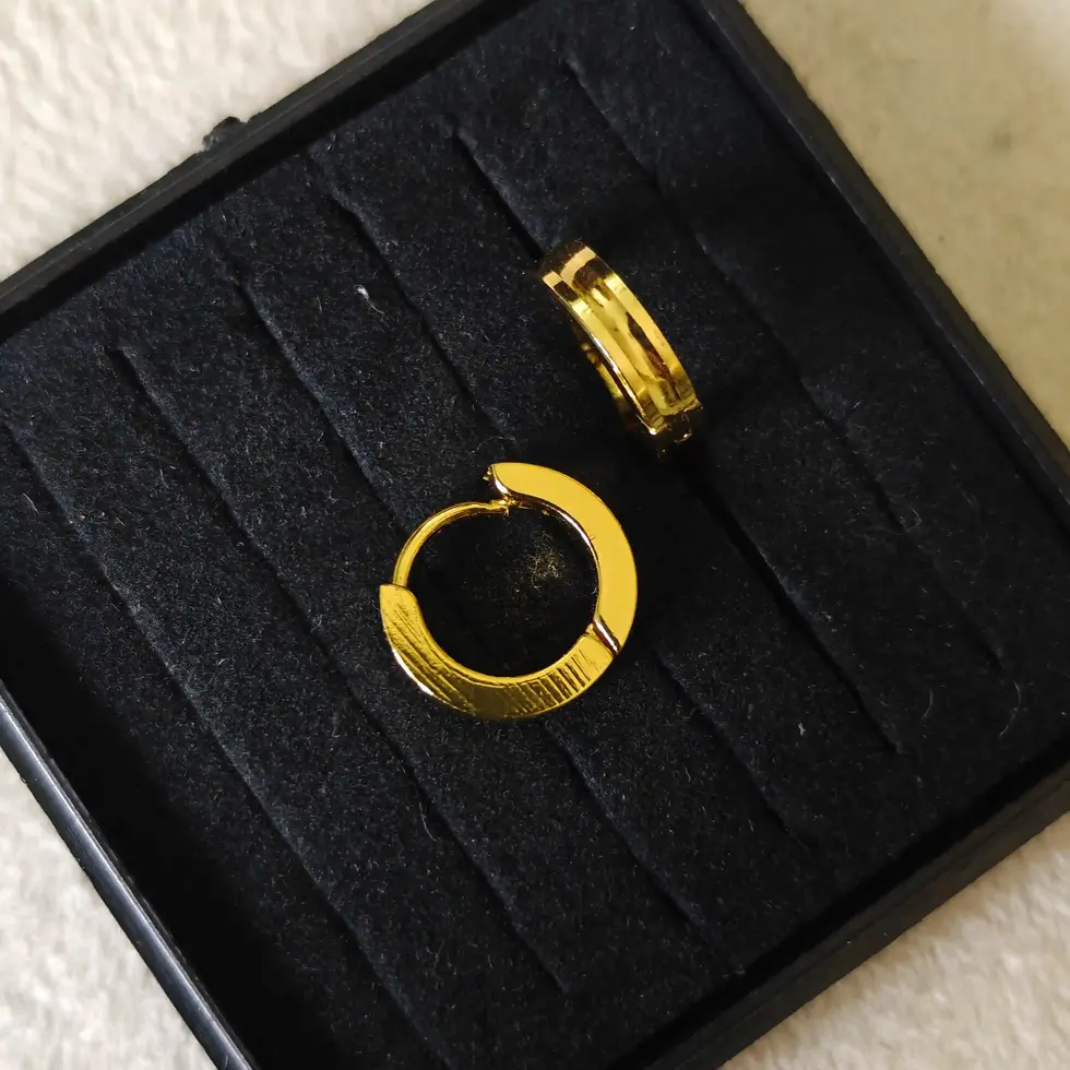 Gold-tone men's hoop earrings featuring a black center stripe, displayed on a neutral background with a modern and masculine