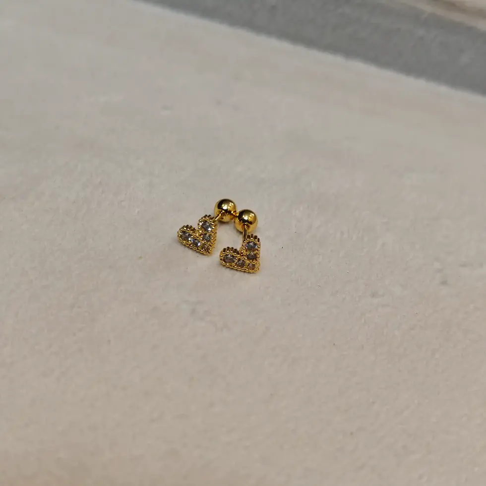 Gold-toned heart-shaped stud earrings with sparkling stones and ball-back screw closure, displayed on a soft surface.