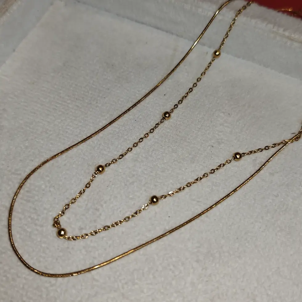 Elegant double-layered gold necklace featuring a sleek snake chain paired with a delicate beaded chain design.
