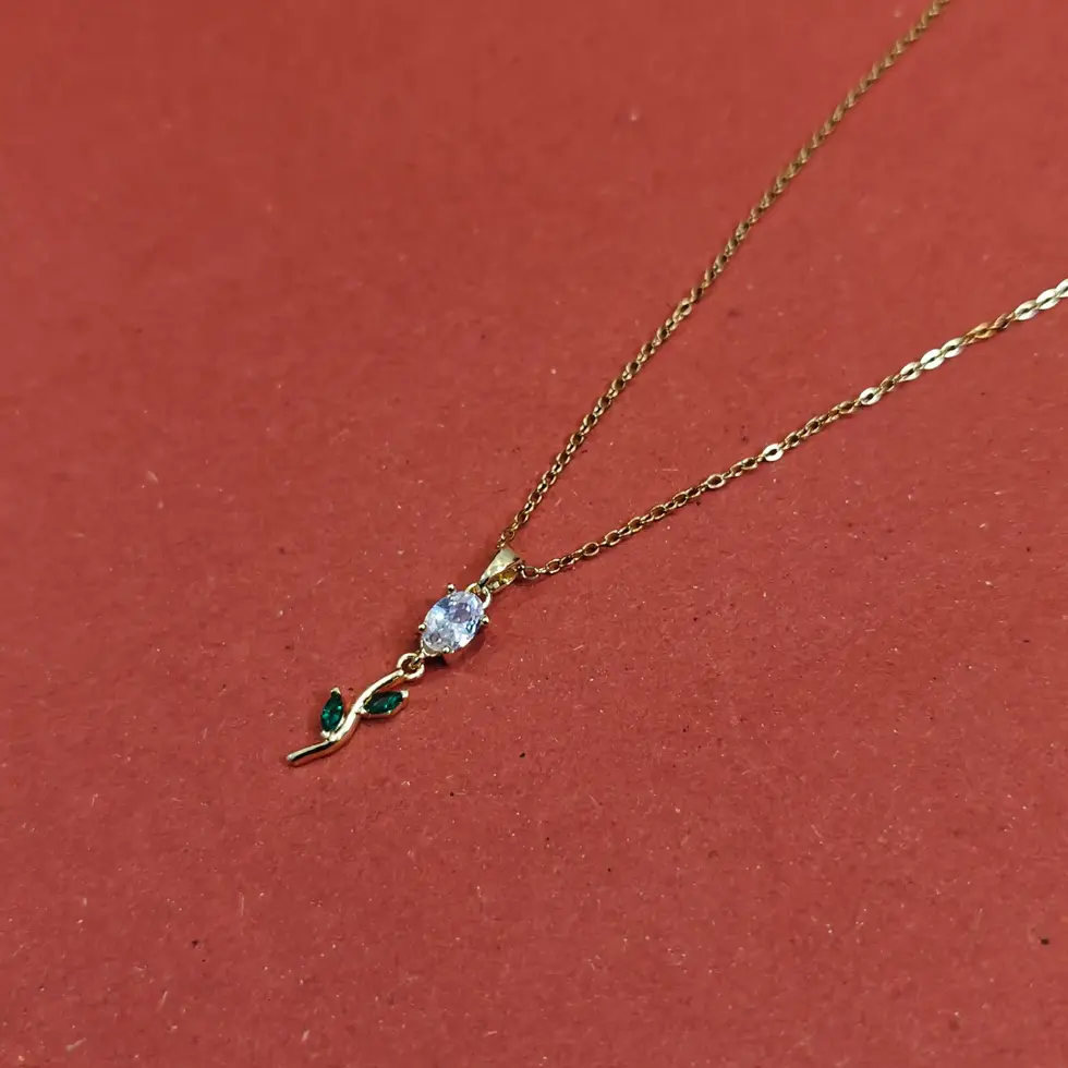 Delicate gold necklace featuring a tulip-shaped pendant with green crystal accents and white stones on a fine chain.