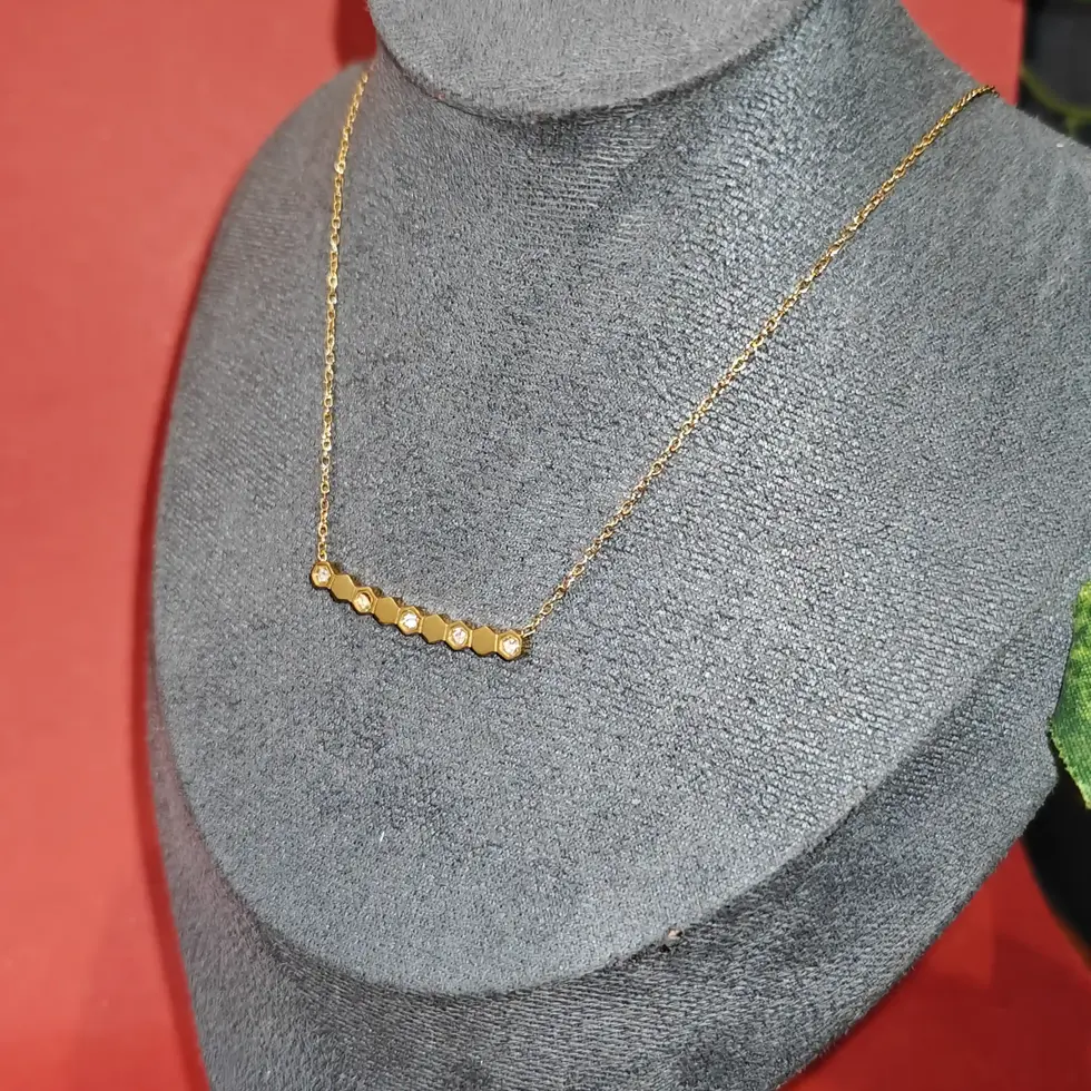 Elegant gold necklace featuring a horizontal row of tiny emerald green stones set closely together on a delicate fine chain.