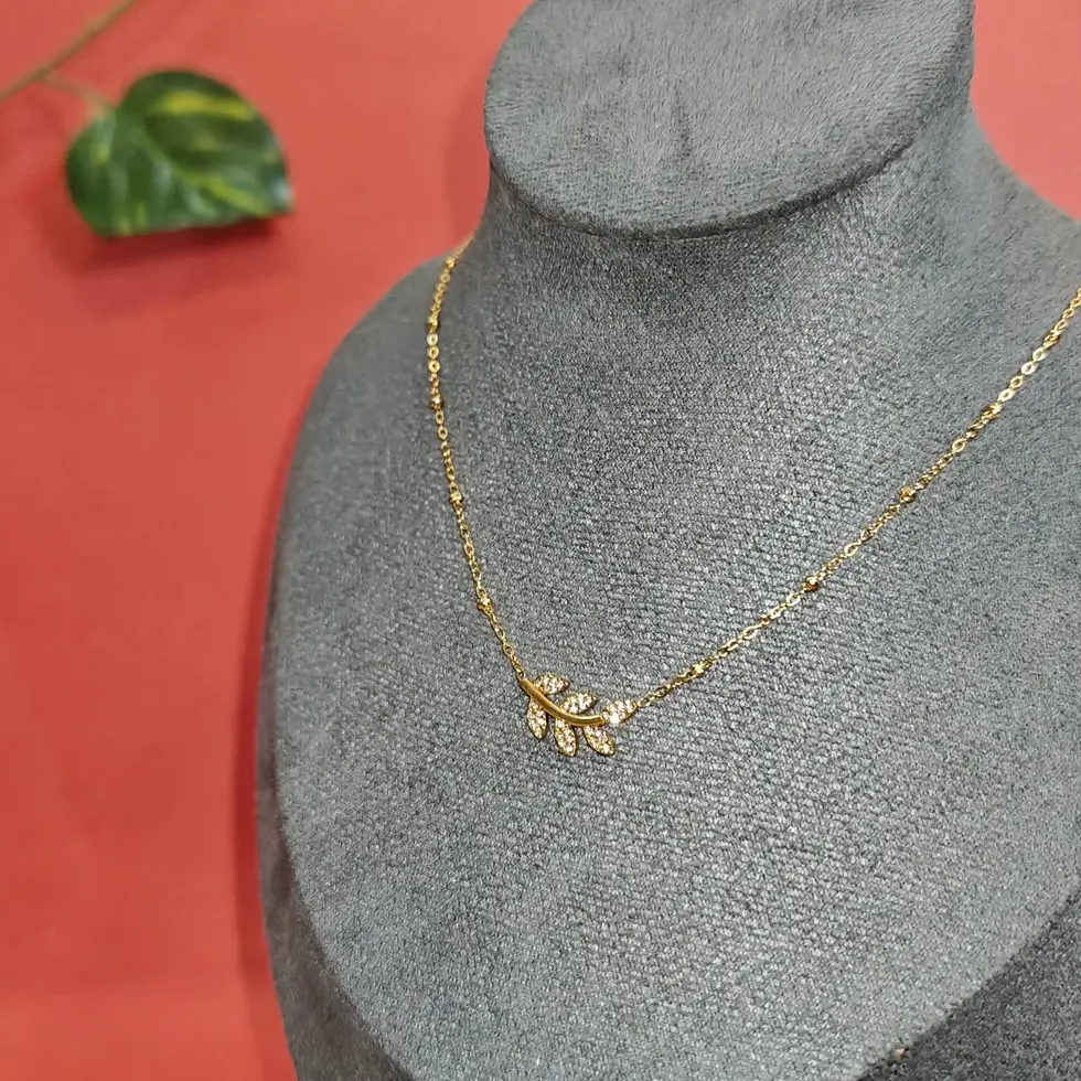 Delicate gold necklace featuring a leafy vine-inspired pendant with shimmering crystal accents on a fine elegant chain.